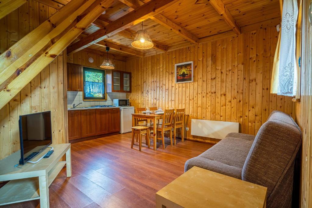 een woonkamer met een bank en een tafel en een keuken bij Omega Domki in Gąski
