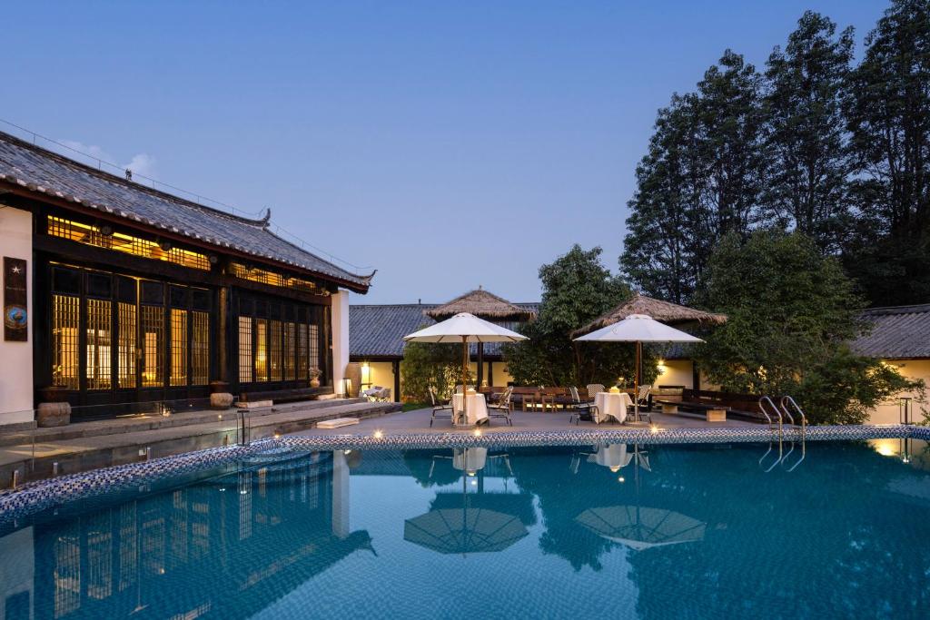a swimming pool in front of a building at 音糖Museum雪山森系隐奢艺术庄园 丽江束河古镇店 in Lijiang