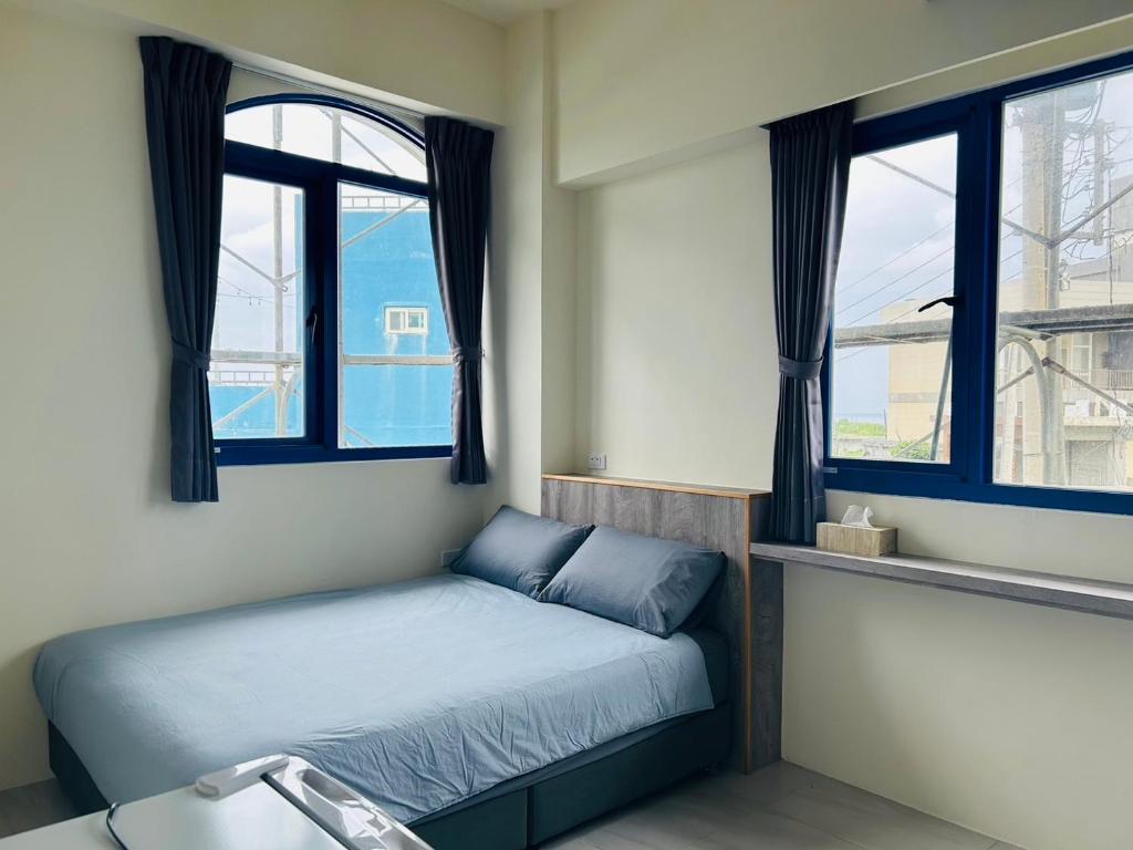 ein kleines Schlafzimmer mit einem Bett und zwei Fenstern in der Unterkunft Corner of Green Island in Green Island