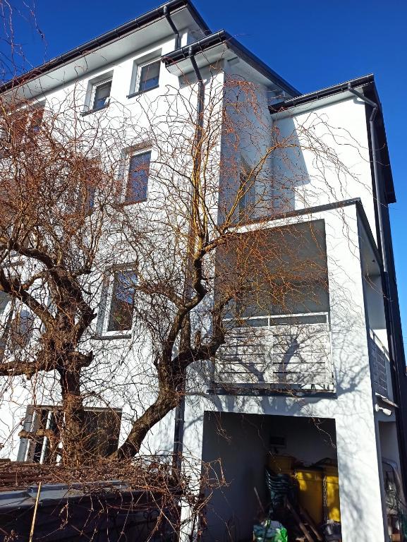 wysoki biały budynek z drzewem przed nim w obiekcie Sercówka Międzyzdroje w mieście Międzyzdroje