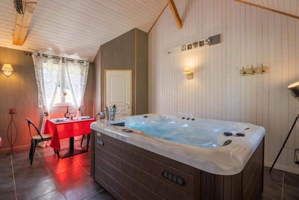een groot bad in een badkamer met een rode tafel bij CHALET DU REV'EAUBOIS in Larche