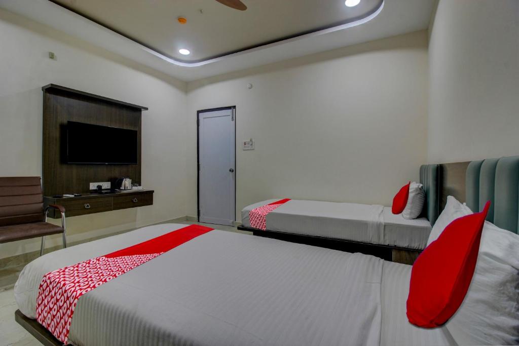 um quarto com 2 camas com almofadas vermelhas e uma televisão em BHILVA INN em Warangal
