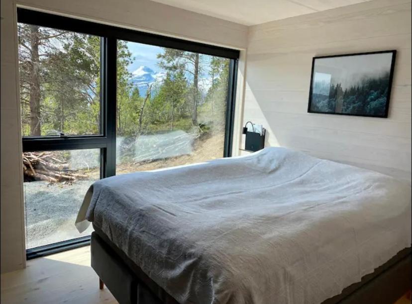 a bedroom with a large bed and a large window at Ny hytte i Malangen in Nordby