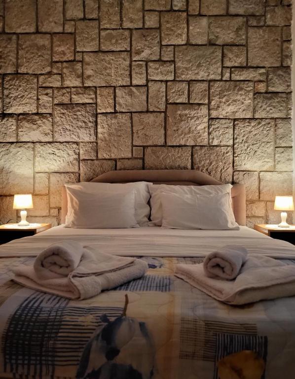 a bedroom with a stone wall with towels on a bed at Apartments Mitrovići Miločer in Sveti Stefan