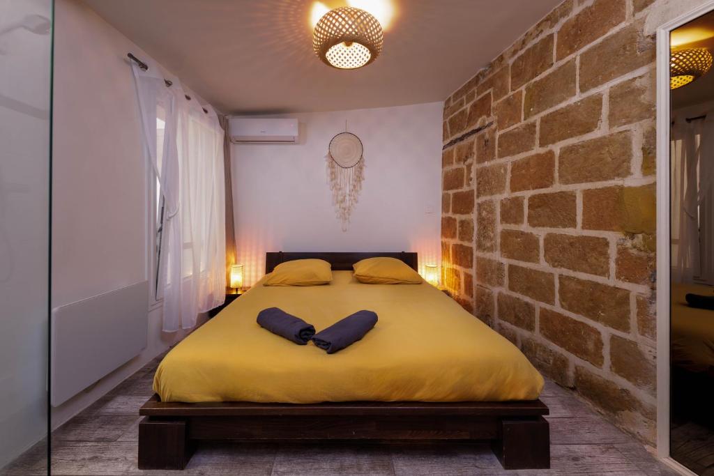 una camera da letto con un grande letto giallo in un muro di mattoni di Le Chapeau Rouge - Centre Historique - Corum - Tramway - Climatisation a Montpellier