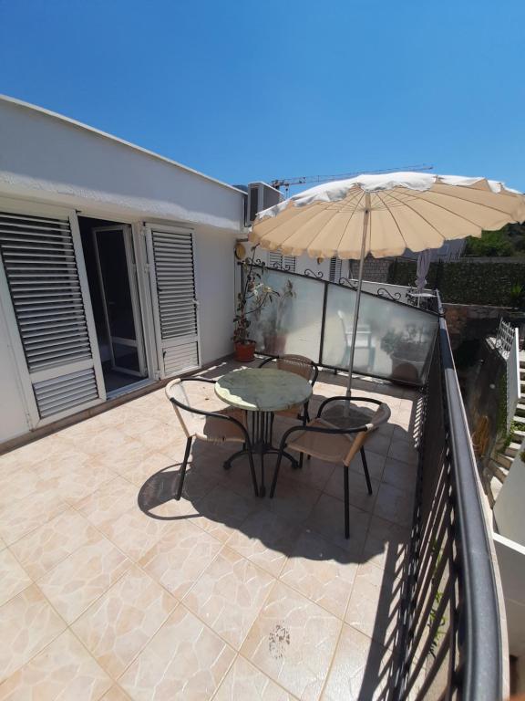 a patio with a table and an umbrella on a balcony at Apartments Mitrovići Miločer in Sveti Stefan