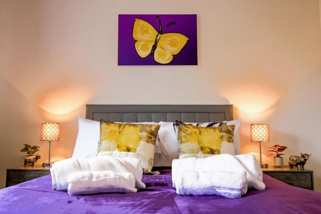 a bedroom with a purple bed with a butterfly painting on the wall at Admirals House - Cosy house in quiet cul-de-sac in Gaywood