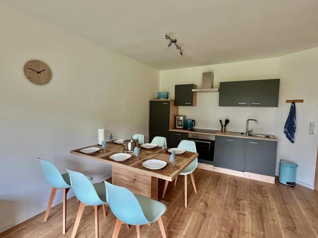 a dining room with a table and chairs and a kitchen at Ferienwohnung am Wald 