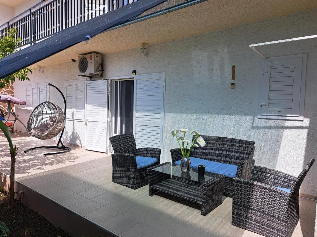 a patio with wicker chairs and a table on a porch at Apartman LETI in Kaštela