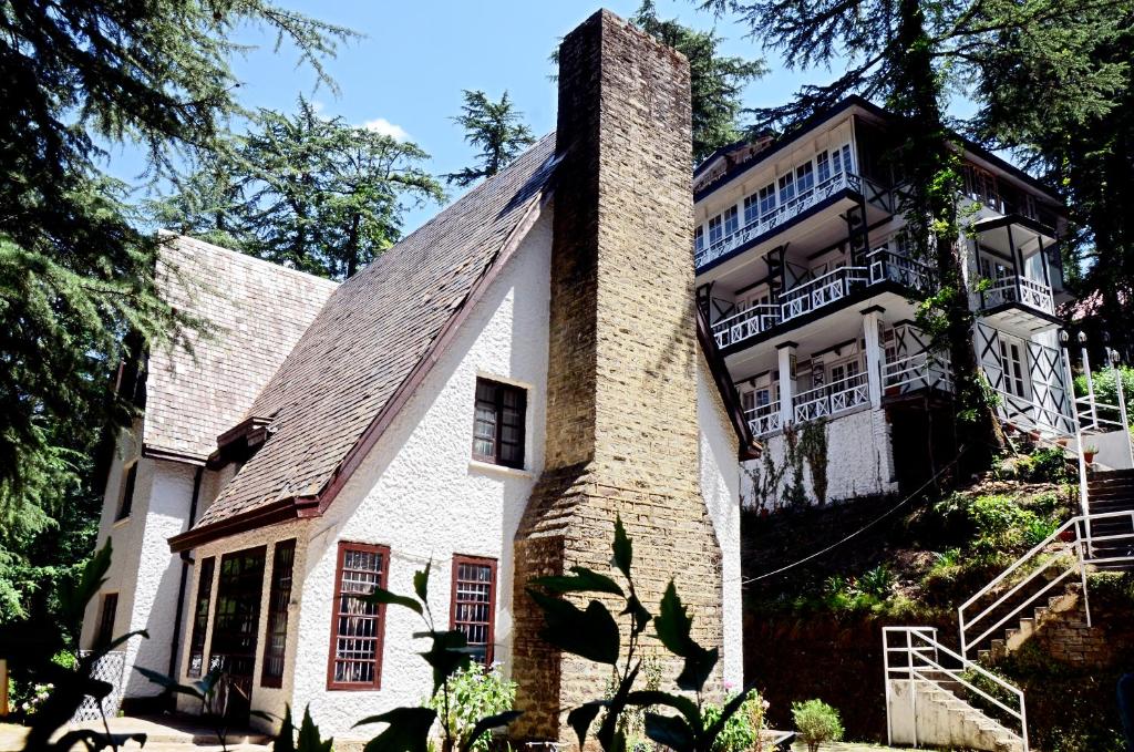 uma grande casa branca com uma chaminé de tijolo em Shimla British Resort em Shimla