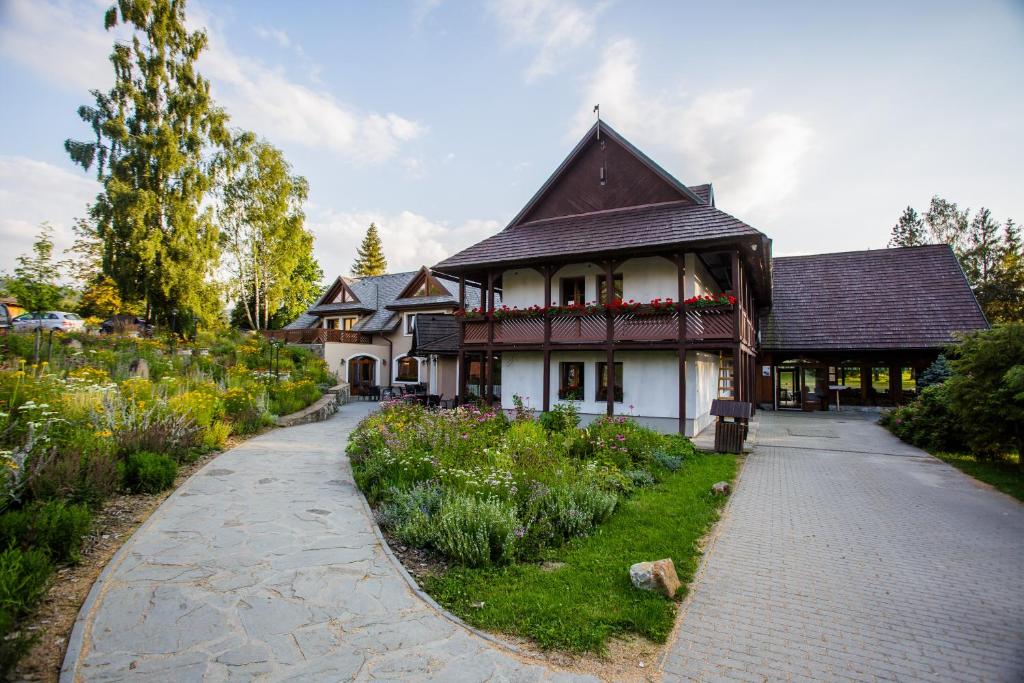 ein Haus mit einem Garten vor einem Gebäude in der Unterkunft Oravský Háj Garden Hotel & Resort in Trstená