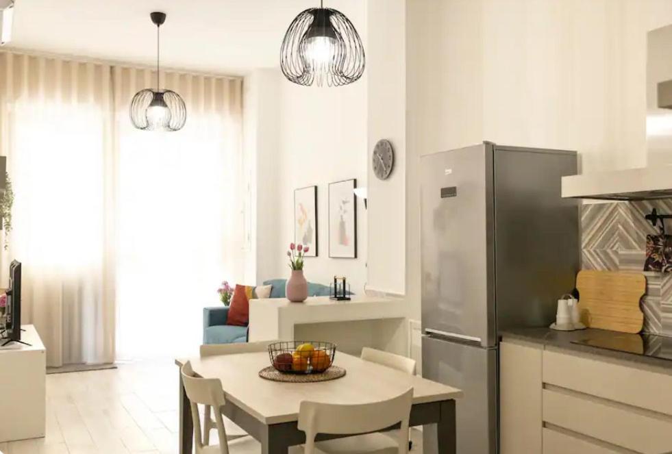 a kitchen and dining room with a table and a refrigerator at Pozzallo cozy house vista mare in Pozzallo