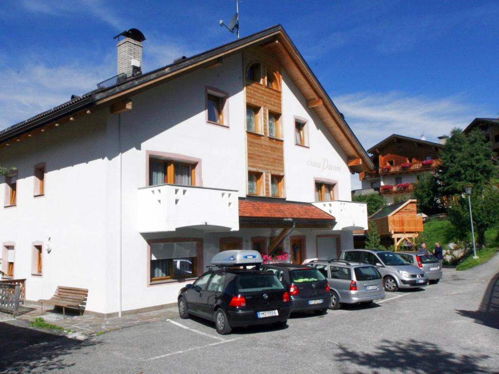 un gran edificio blanco con coches aparcados en un aparcamiento en Ciasa Parom, en San Cassiano