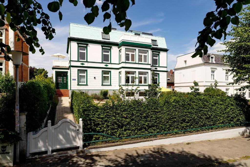 ein weißes Haus mit einem Zaun davor in der Unterkunft Ferienwohnungen in der Villa Lindenallee 9 in Malente