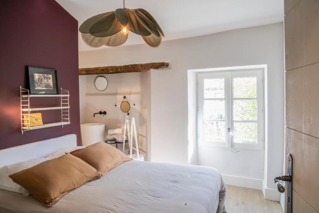 ein Schlafzimmer mit einem weißen Bett und einem Fenster in der Unterkunft La Maison Favier in Saint-Rémy-de-Provence