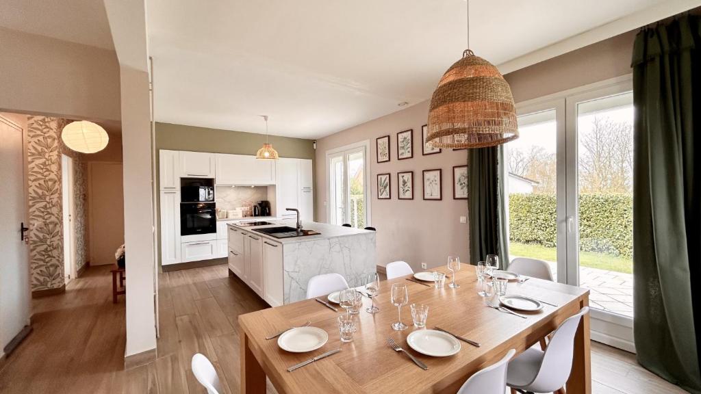 ein Esszimmer mit einem Tisch und einer Küche in der Unterkunft Maison avec jardin: La cabane aux oiseaux in Saint-Valery-sur-Somme