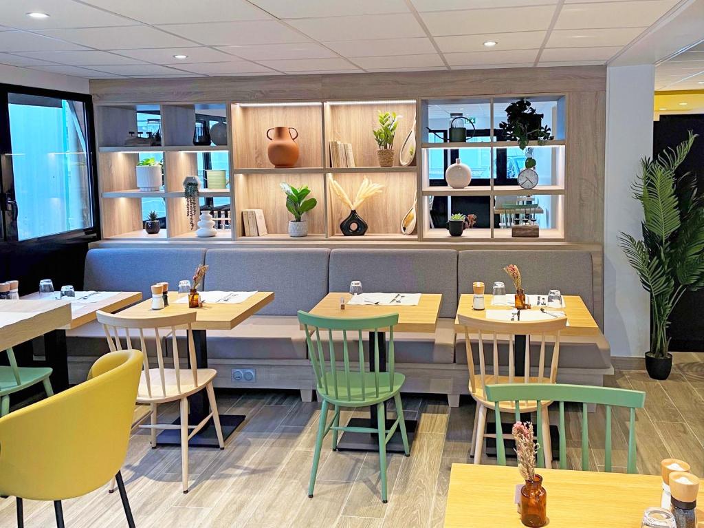 um restaurante com mesas de madeira e cadeiras verdes em Campanile St Etienne Centre - Villars La Terrasse em Villars