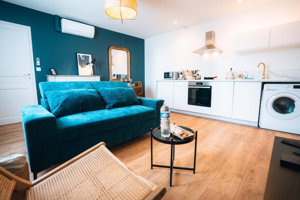 ein Wohnzimmer mit einem blauen Sofa und einem Tisch in der Unterkunft Le Blue Berry • Élégant & Fonctionnel • Proche Gare in Châteauroux