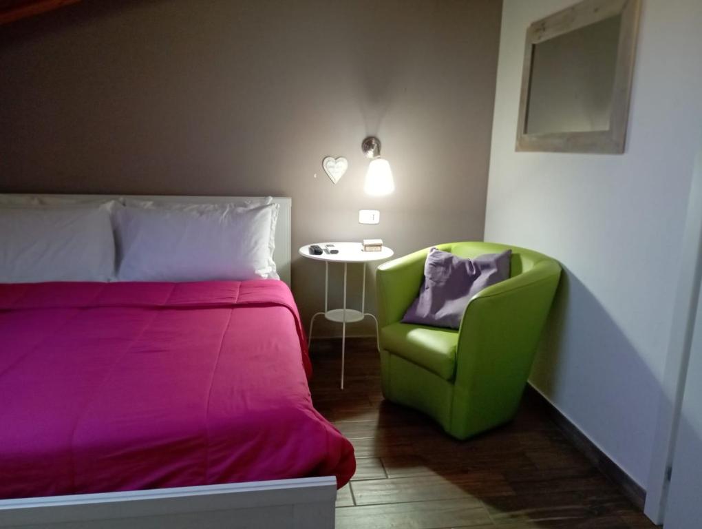 a bedroom with a bed and a green chair and a table at A due Passi dalla Stazione e dal Centro in Novara