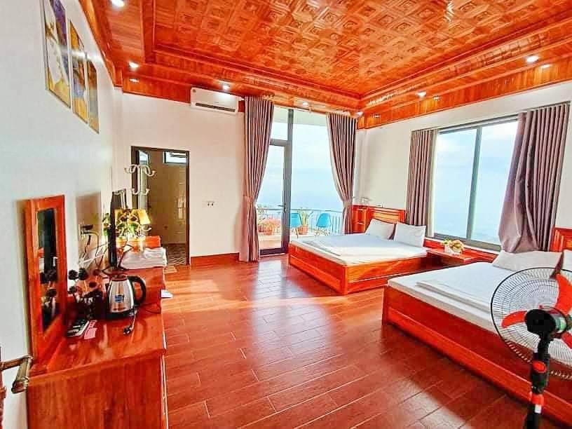 a large bedroom with two beds and a large window at Ruby Tam Đảo in Tam Ðảo