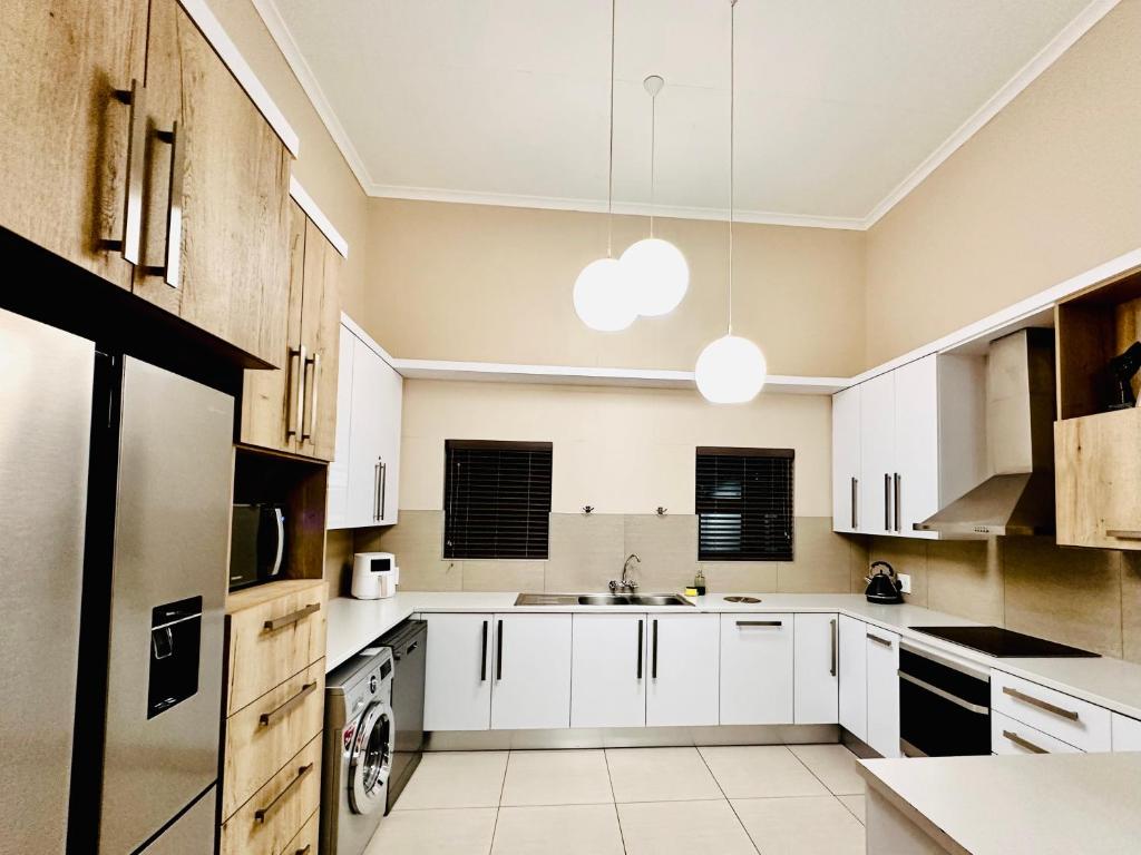 una cocina con armarios blancos y fregadero en Upmarket apartment in the heart of Windhoek, en Windhoek