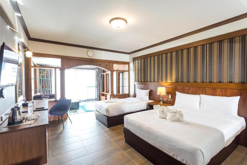 攀牙Le Erawan Phang Nga Hotel的有两张床和一台电视的酒店房间