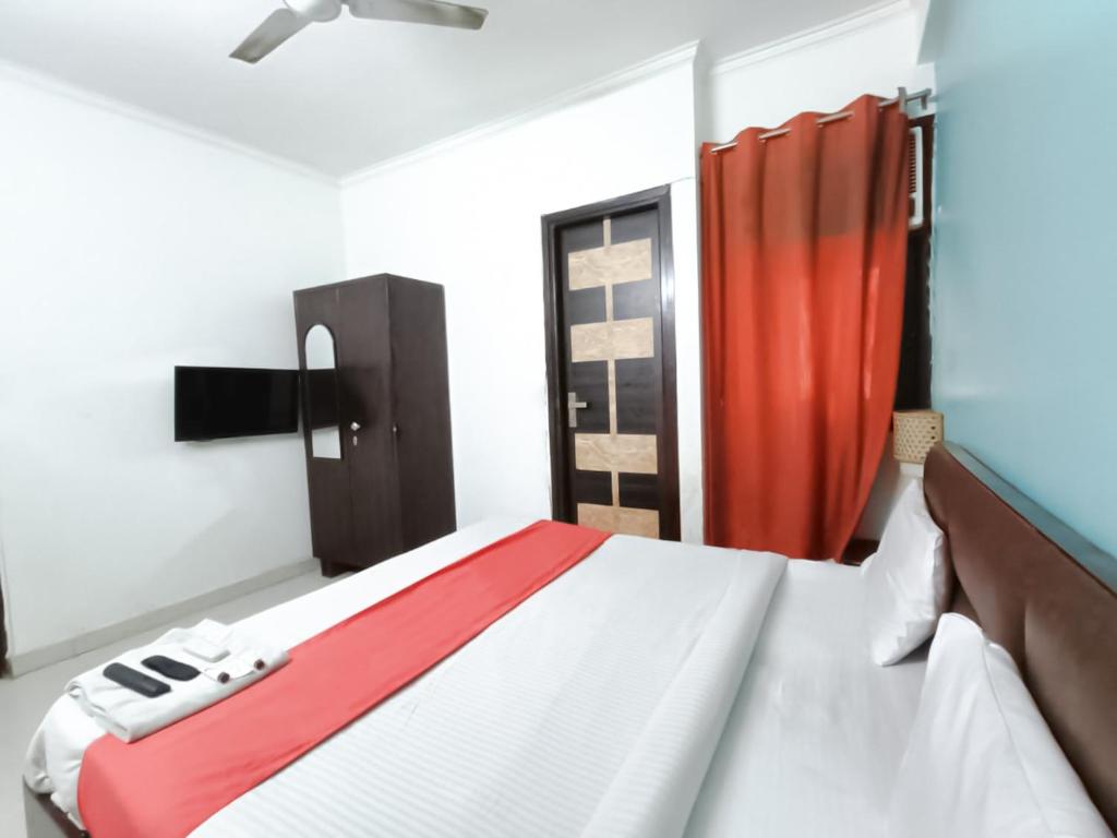 a bedroom with a bed and a red curtain at Roomshala 172 Hotel Blue Moon - Satya Niketan in New Delhi