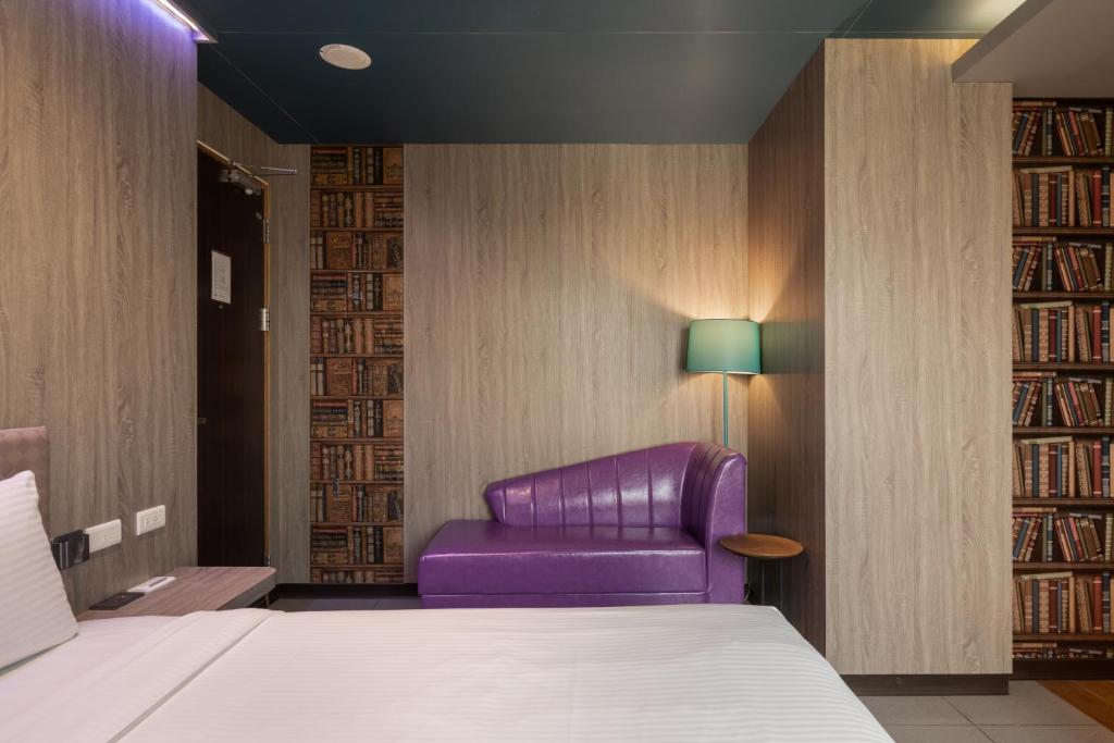 a bedroom with a bed and a purple chair at S&amp;E Hotel in Tainan