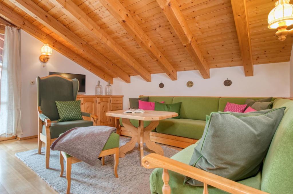 una sala de estar con muebles verdes y techo de madera. en Bergw8, en Reit im Winkl