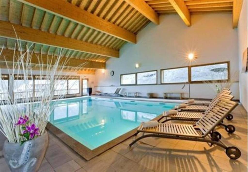 a large swimming pool with two lounge chairs next to it at Appartements montagne, piscine et sauna in Orelle