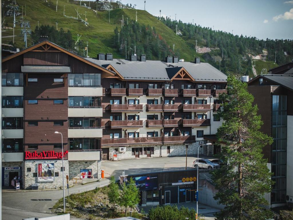 un edificio de apartamentos con una montaña en el fondo en Ski-Inn RukaVillage, en Ruka