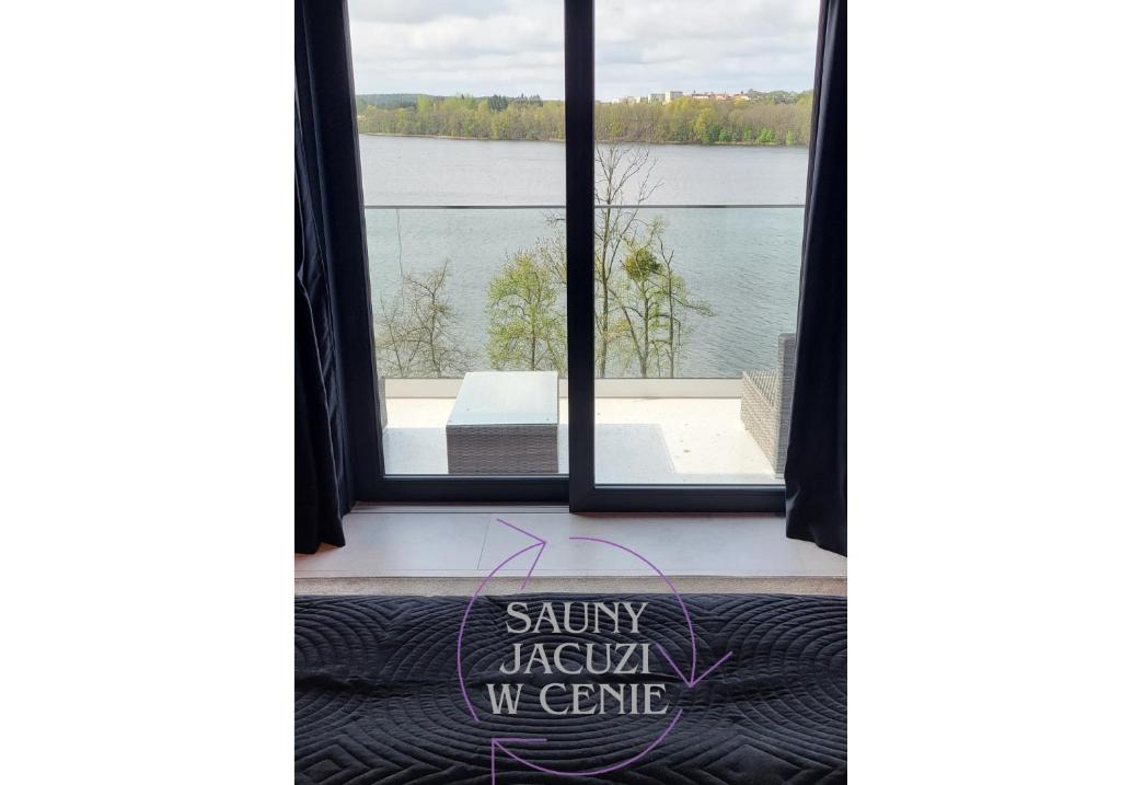 a room with a window with a view of a lake at High Class Suites Mazuria in Mrągowo