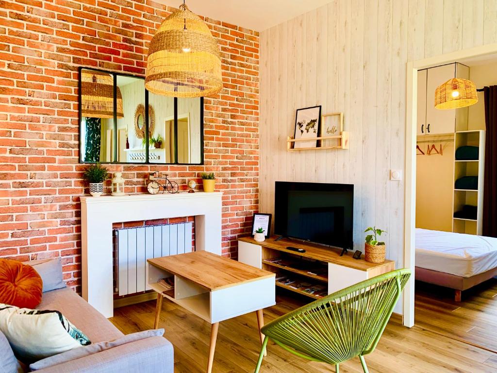 a living room with a brick wall and a television at Gîte Clair de Lune in Monts-sur-Guesnes