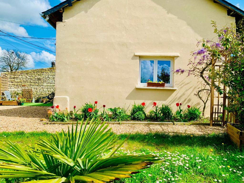 dom z oknem z kwiatami na dziedzińcu w obiekcie Gîte Clair de Lune w mieście Monts-sur-Guesnes