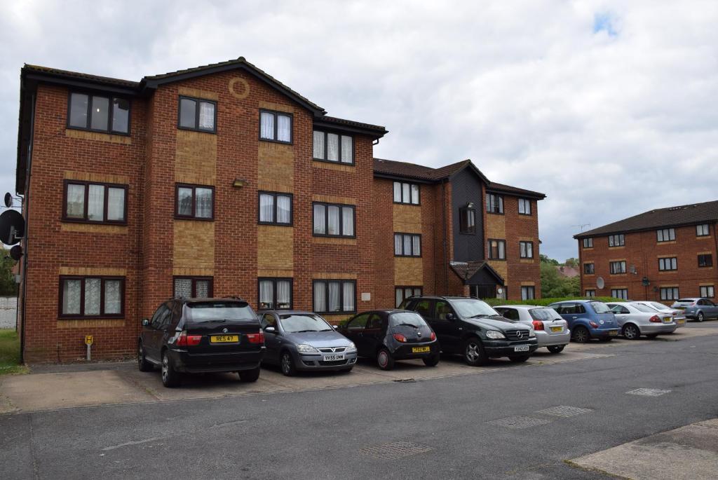 een rij auto's geparkeerd voor een bakstenen gebouw bij One Bedroom Flat, Granary Road in Ponders End