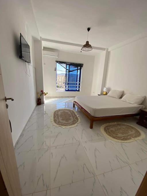 een grote witte kamer met een bed en een televisie bij Location juste pour les familles in Mostaganem