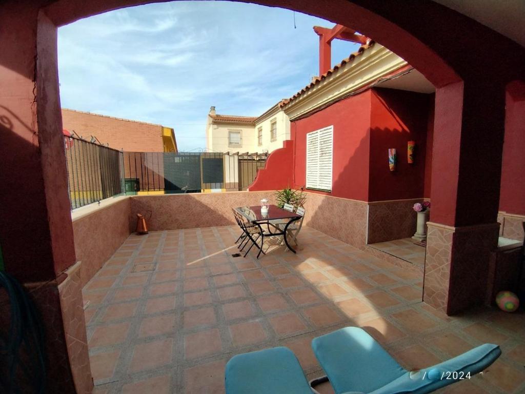 un patio con sillas y una mesa en un edificio en "Casa Colorá" en Sevilla, en Benacazón
