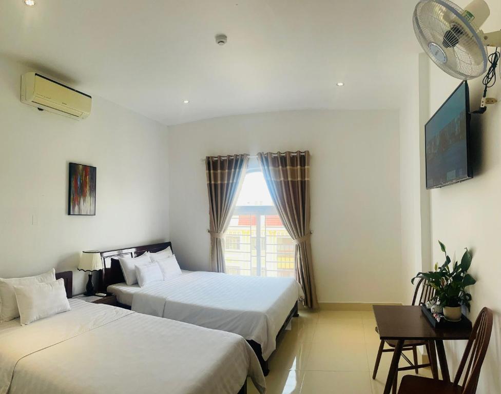a hotel room with two beds and a window at KHÁCH SẠN ROMO in Quang Ngai
