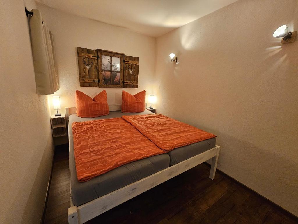 ein kleines Schlafzimmer mit einem Bett mit orangefarbener Bettwäsche in der Unterkunft Ferienwohnung Struppi Sächsische Schweiz in Struppen