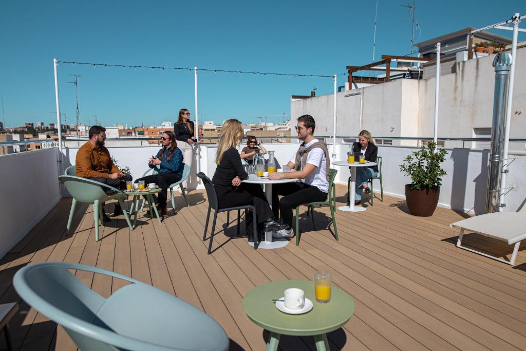 a group of people sitting at tables on a roof at Aila II Hotel Boutique by SingularStays - Digital Access in Burjasot