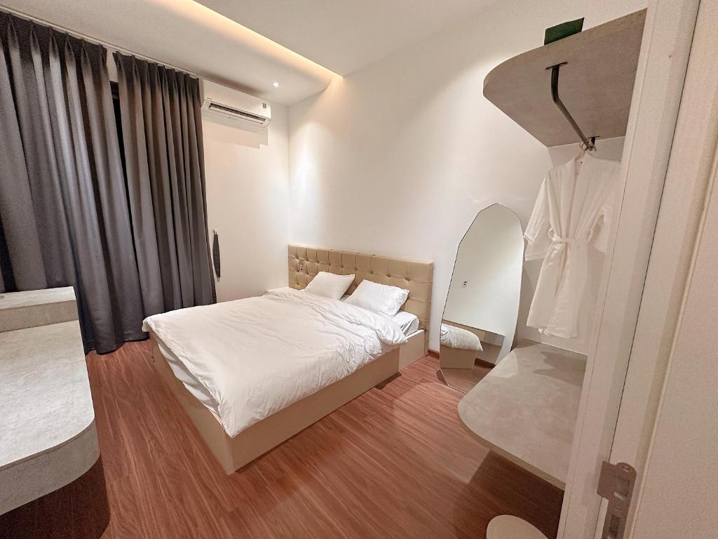 Dormitorio pequeño con cama y espejo en Malloire House Hue, en Hue