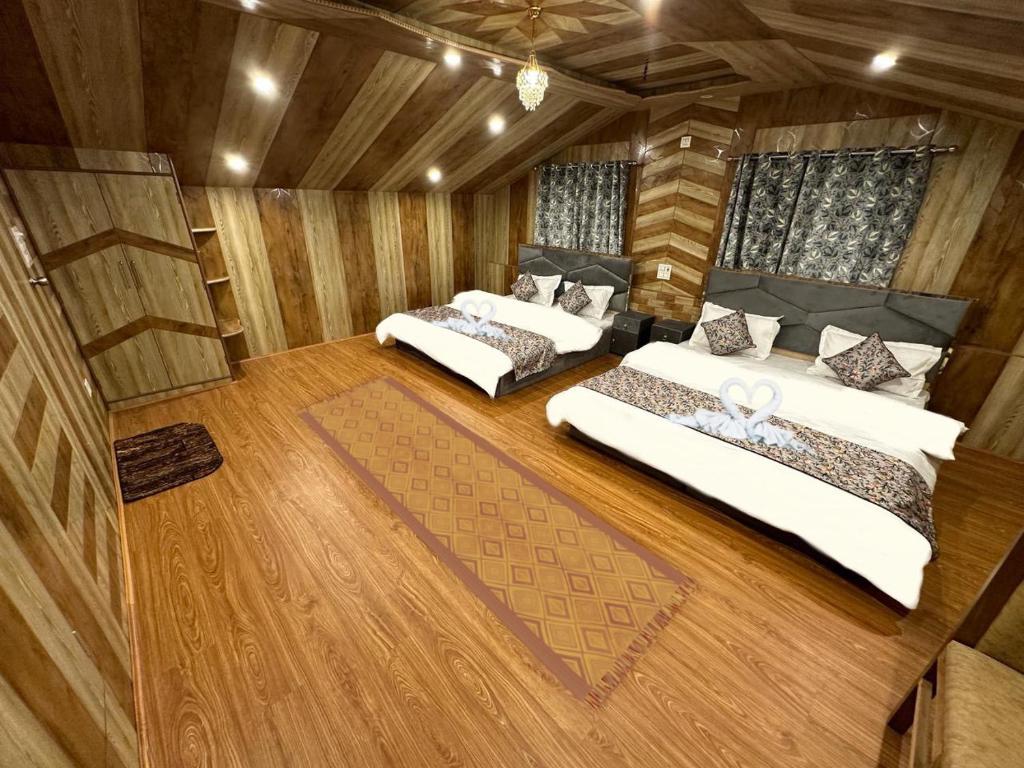 three beds in a room with wooden walls and wood floors at Faizzy's residency in Srinagar