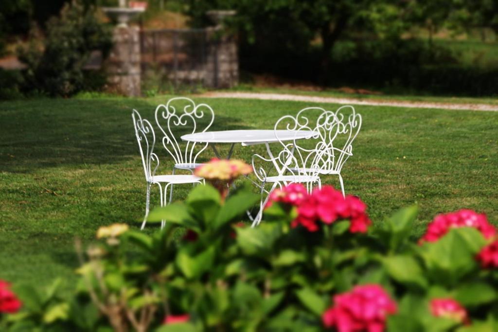 een tafel en stoelen in een tuin met bloemen bij Le Gîte de Lardois in Miers