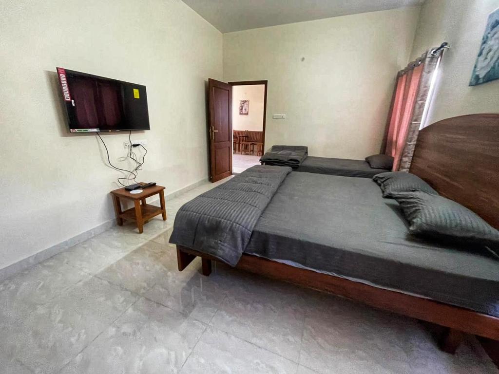 a bedroom with a large bed and a flat screen tv at Vacation villa in Kodaikānāl