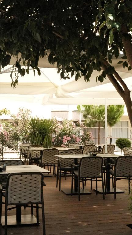 an outdoor patio with tables and chairs and an umbrella at Hotel A&#39;mare in Zadar