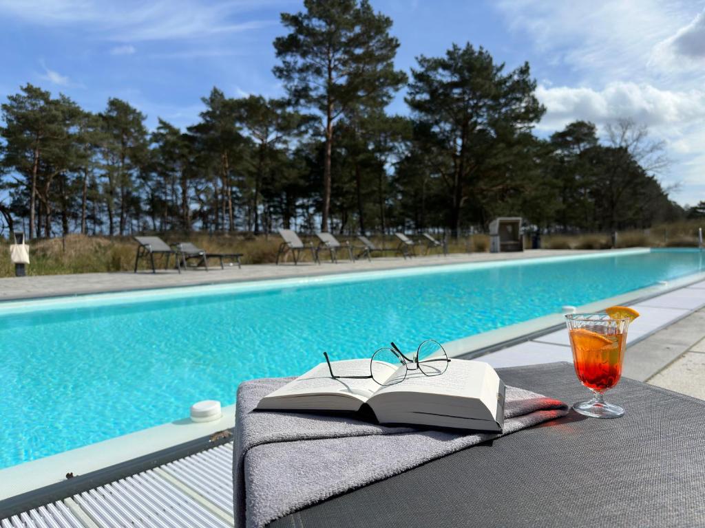een boek en glazen op een tafel naast een zwembad bij Inselloft-Rügen in Binz
