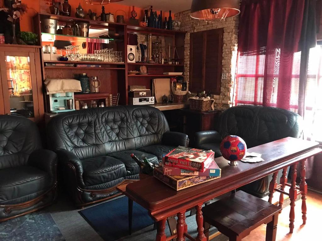 a living room with black leather couches and a table at Blue House Apartman Kék Ház Üdülő in Dunapataj