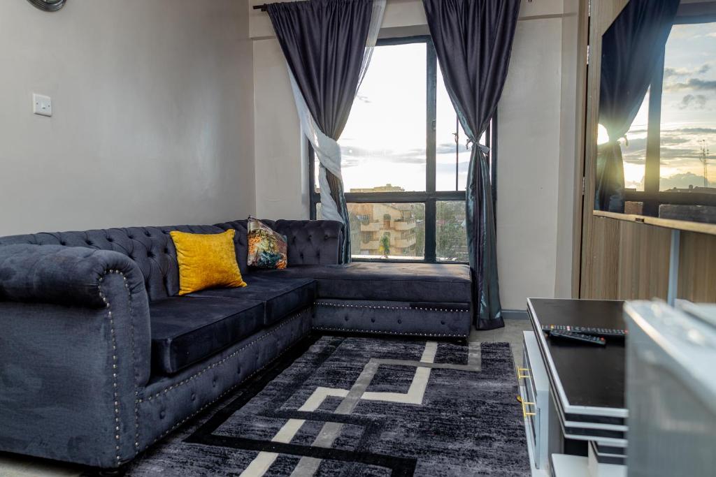 ein Wohnzimmer mit einem schwarzen Sofa und einem gelben Kissen in der Unterkunft Cherry Home Stays KE in Nairobi