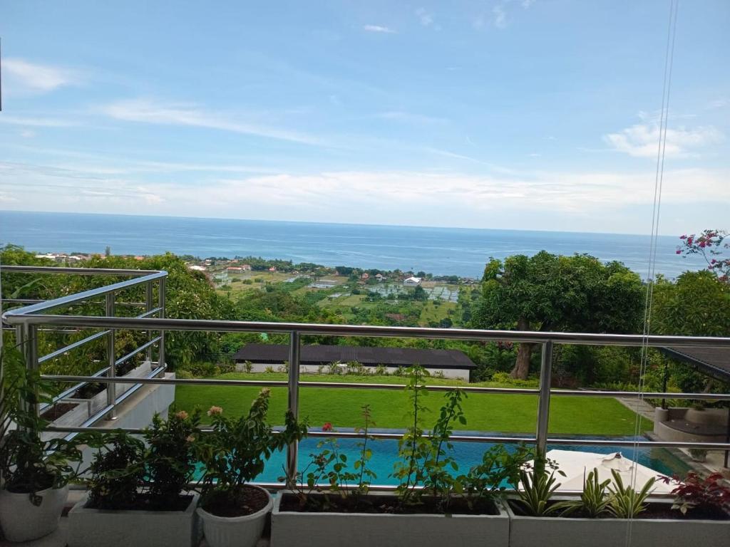 a balcony with a view of a pool and the ocean at Villa Puri Soka in Pabean Buleleng
