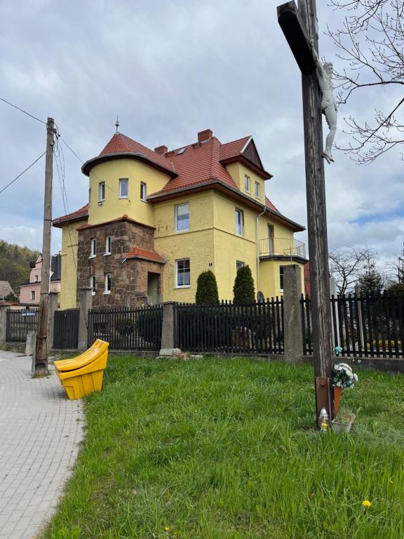 ein großes gelbes Haus mit rotem Dach in der Unterkunft Noclegi w Bardzie in Bardo